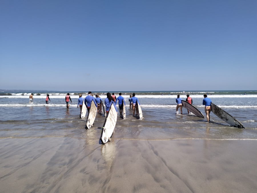 People walking into ocean with surfboards in Canggu Bali