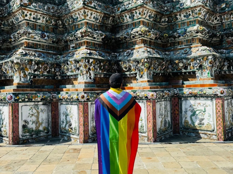 Tour guide stood by Wat Arun in Thailand with Pride flag