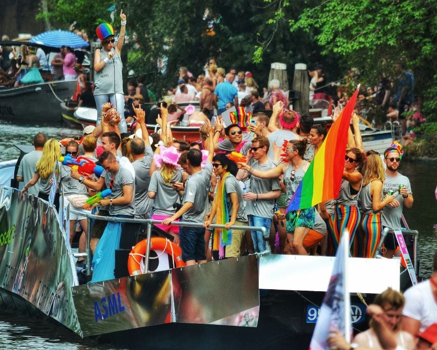 People on a LGBTQIA+ float down canal in Amsterdam