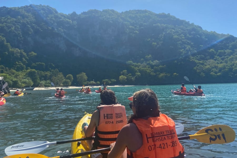 Travellers canoe around lush green islands