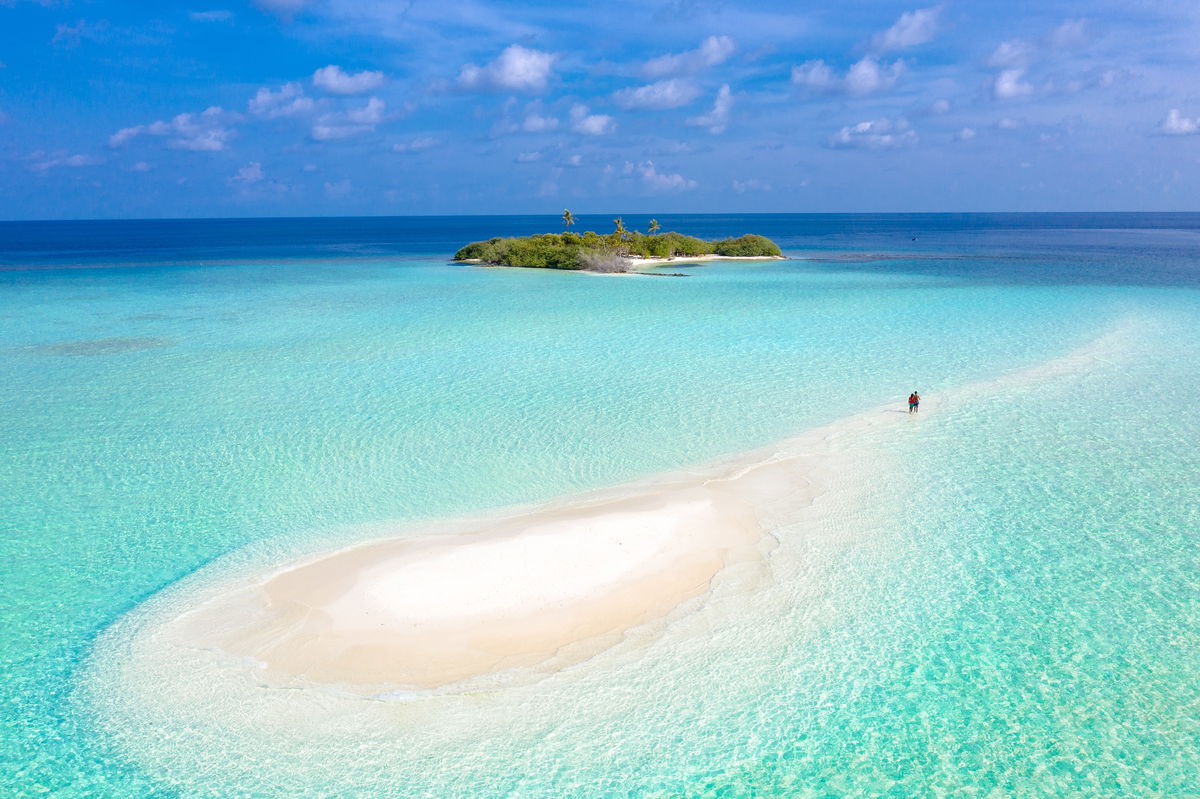 Landscape of people walking on the spit of a beach in the Maldives